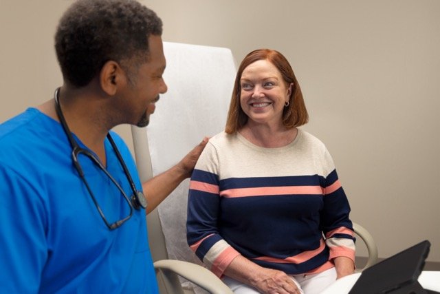 White female patient with black male nurse in doctors office