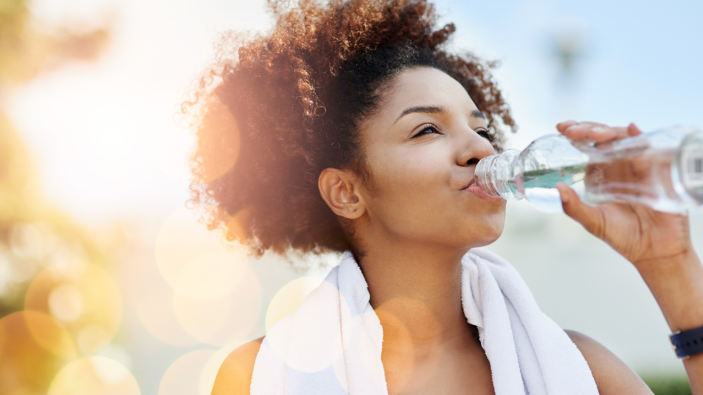 A woman with curly hair drinking water