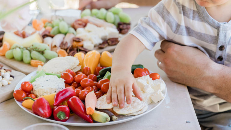 child grabbing food off a platter.