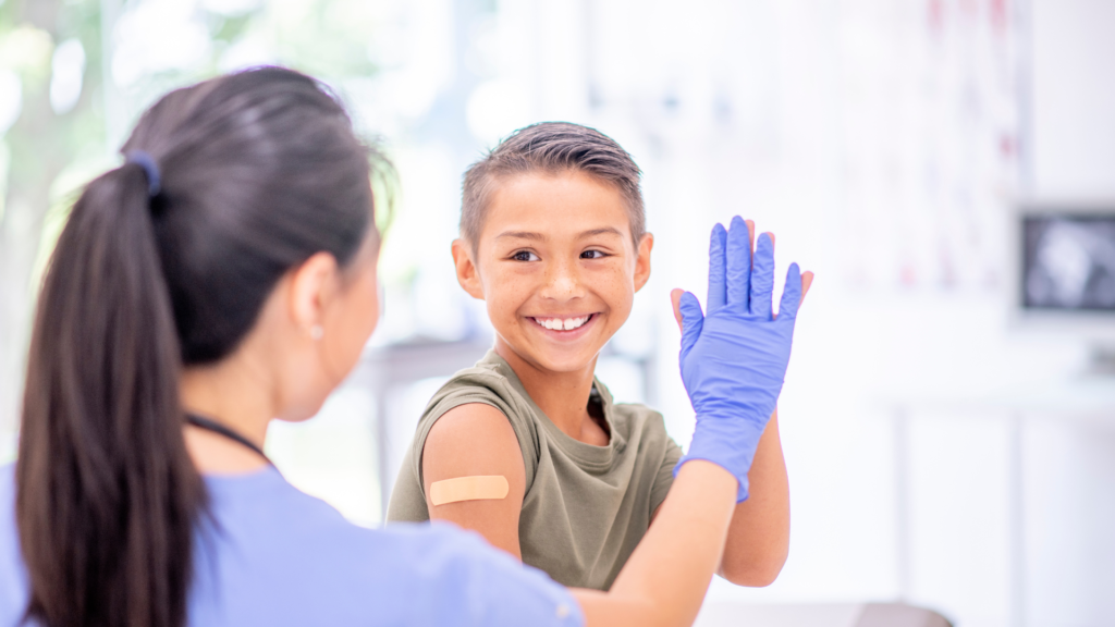 Doctor giving a high five to a child with a bandaid on their arm