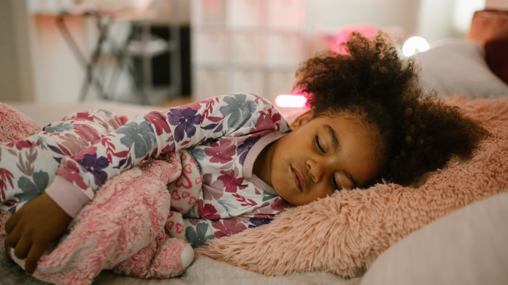 Curly haired child sleeping in bed.