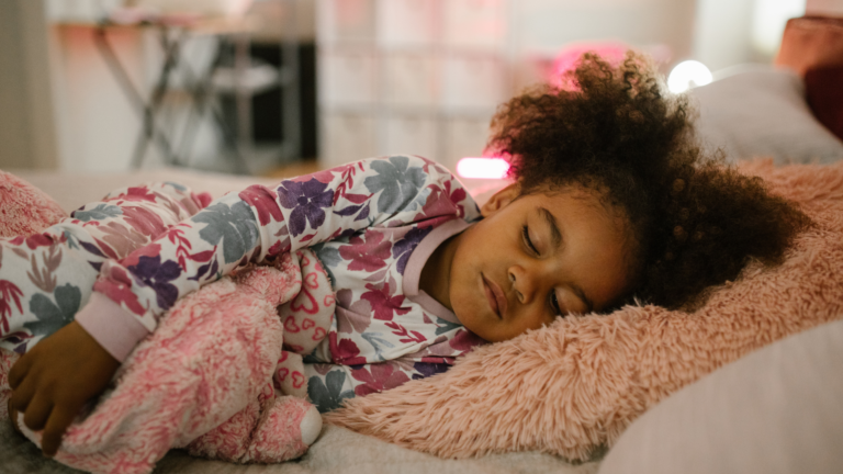 Curly haired child sleeping in bed.
