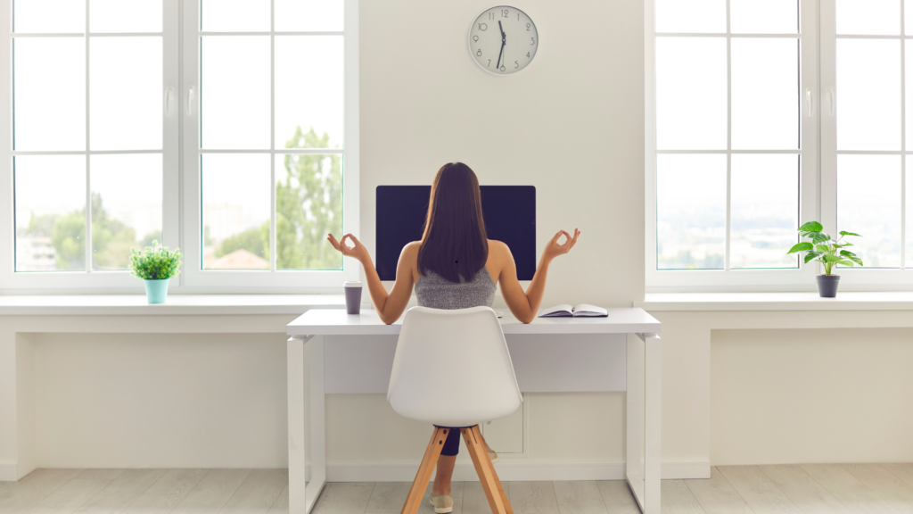 a women in a modern, clean office setting with her back to the picture in a desk chair.